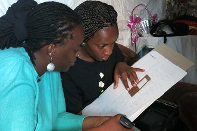 Low-income woman in Kenya looks at prototype, which is a physical representation of a product or service to be tested with actual customers before a product or service is brought to scale.