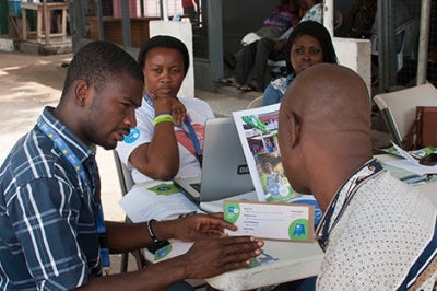 Tito Cash representative teaches a mobile money user in Ghana about USSD long codes, providing positive customer service to a customer in a low-income segments