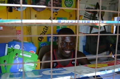 A smiling mobile money agent in Ghana provides good customer experience and a customer-centric attitude at his Tigo Cash booth 