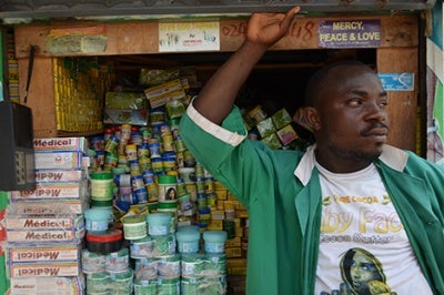 Entrepreneur in Ghana stands in front of his shop, discussing financial products and services that meet the needs of low-income customers