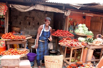 Woman entrepreneur in her vegetable stall provides customer-centric service to her customers.