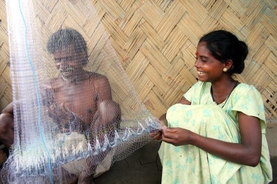 low-income man and woman repair fishing nets, a daily task for small business entrepreneurs.